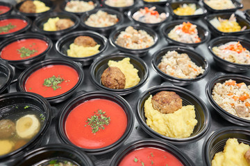 Food delivery. Different in plastic disposable lunch box with healthy natural food. Chicken broth, mashed soup, mashed potatoes with cutlet, seafood pasta, salads, pilaf with a fresh bun.