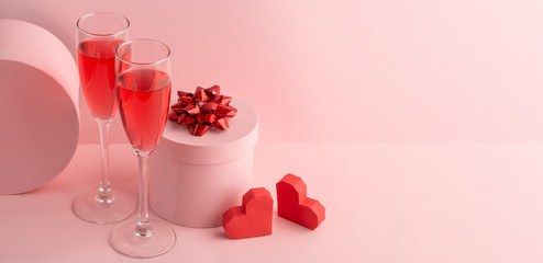 Fototapeta na wymiar Round gift box, glasses of red prosecco and two hearts on pink