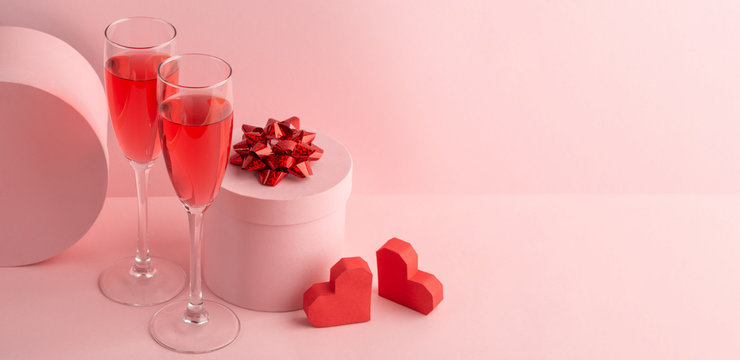 Round gift box, glasses of red prosecco and two hearts on pink