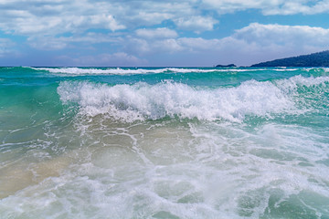 Big tropical green ocean wave with cloudy sky background
