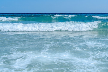 Big wave of ocean on sandy beach with clean sky