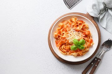Pasta fettuccine with tomato sauce with parmesan and basil in rustic style on white background. View from above. Space for text.