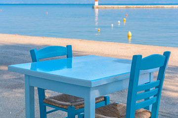 Blue table and chairs in a typical tavern in Greece with sea background