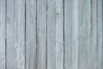 Fototapeta na wymiar Part of an old fence of painted wooden boards on the street. Old wooden fence made of flat boards. Faded texture with turquoise paint. Copy space. Selective focus