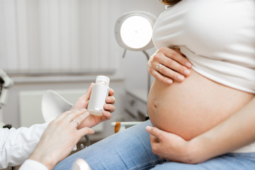 Doctor holding some medicine or supplements for a pregnant woman during a consultation, close-up...