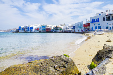 Beautiful sandy beach on Greek Island of Mykonos with port bay and city skyline