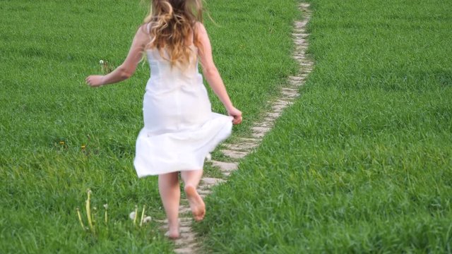 girl in a long white dress on a green field