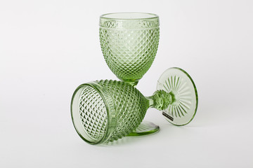 two empty glasses of green glass on a stem on a white background