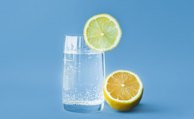 translucent glass of water with gases and bubbles, with a round slice of lemon on a glass and a...