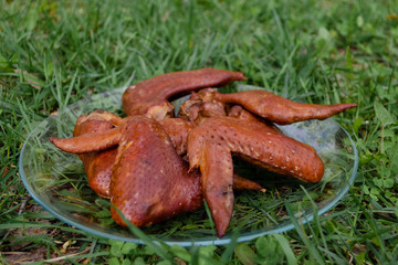 Smoked chicken. Smoked chicken wings lie on a plate. The process of cooking outdoors. Cooking at the stake.