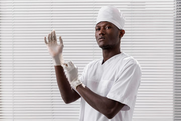 Specialist male doctor putting his gloves. Black health professional, afro american doctor, african nurse.
