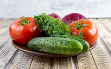 Plate with fresh vegetables close-up on a wooden background.