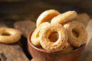 Puff pastry sprinkle with sugar in a wooden bowl on a brown wooden background. Cookies sprinkle with sugar close-up. Sweet pastries