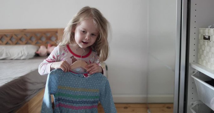 Little beautiful girl with white hair chooses clothes in the closet