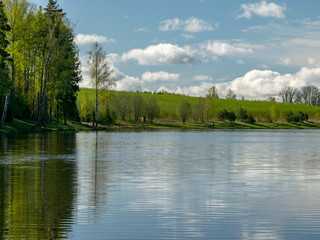 peaceful spring landscape with a clear lake and beautiful reflections of clouds and trees