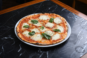 pizza with arugula slices and mozzarella slices on a black marble table