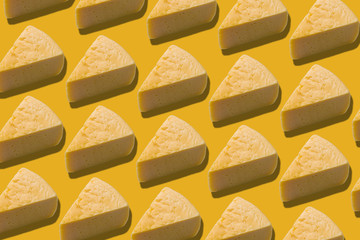 Pattern with slices of cheese, closeup, yellow background.