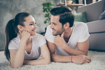 Closeup photo of beautiful lady handsome guy friendly couple stay home quarantine time lying comfy floor fluffy carpet leaning head hands look eyes toothy smiling living room indoors