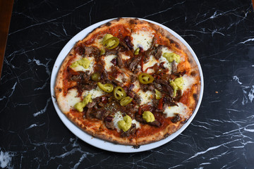 pizza with jalapeno peppers, chicken, cheddar and pizza sauce on black marble floor