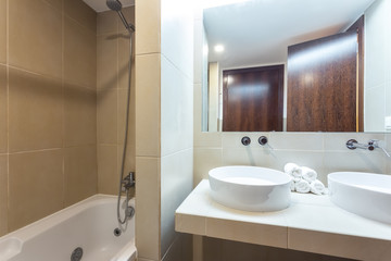 Modern bathroom with bathtub, mirror and washbasin. European hotel design.