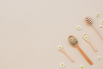a wooden spoon and chamomiles on a beige background, concept of healthy eating, top view. Flat lay, Chamomile herbal tea.