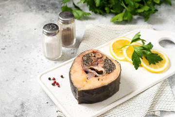 Wild sturgeon steak on a white ceramic plate on the light gray kitchen table. Healthy seafood. With space for text