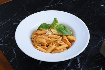 italian cuisine, noodles on a black background, served with meat, chicken, vegetables, greens, cheese, sauce, red pepper