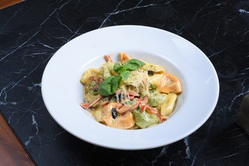 italian cuisine, noodles on a black background, served with meat, chicken, vegetables, greens, cheese, sauce, red pepper