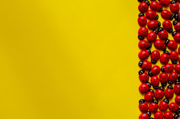 decorative wooden ladybugs on yellow background with copy space. Ladybug pattern.