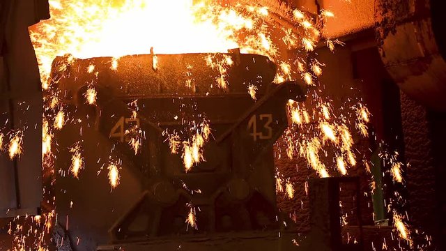 Hot metal molten iron was poured into the furnace in the steel plant,sparks splashed.