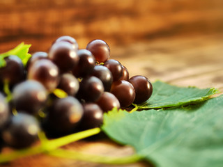 Grapes on a wooden table. Fresh branch of red grapes with leaves
