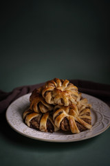 Fresh pastries, hot tasty cinnamon rolls on a green background with a burgundy dishcloth. Buns for dessert for hot drinks. Top view.