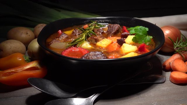 Meat stew with vegetables. Beef stew with potatoes, carrots and fresh herbs on table.