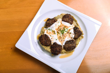 spicy meatballs with yogurt and mashed potatoes on a serving plate