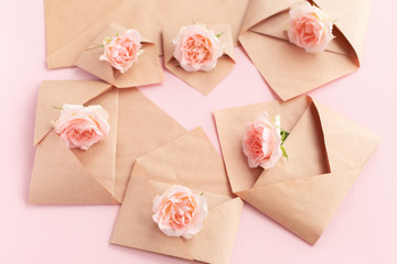 Paper open craft paper envelopes with full small rose flowers on color background. Trend spring, summer concept. Romance, love notes, greeting card for March 8 International Woman's, Valentine's day