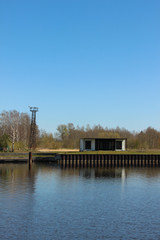 Fototapeta premium One-storey modular house that stands at the river shore. Container housing that stands aside from the living area.