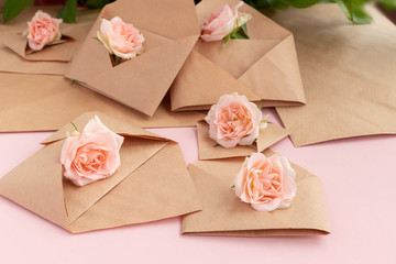 Obraz na płótnie Canvas Paper open craft paper envelopes with full small rose flowers on color background. Trend spring, summer concept. Romance, love notes, greeting card for March 8 International Woman's, Valentine's day