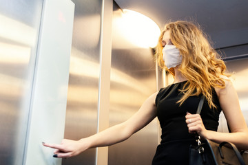 Business woman wearing protective white face mask is using elevator