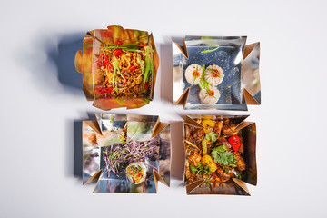 top view of tasty and spicy chinese food in takeaway boxes on white