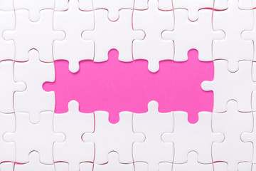 White jigsaw puzzle with empty space for text and pink background