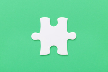 One white jigsaw puzzle piece on green background