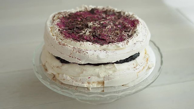 Kid tase delicious Meringue Cake from a plate by finger. Decorated with chocolate and forrest fruits