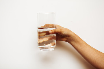 A woman's hand holds a glass of water on a dark background