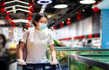 Asian woman shopping for groceries in the market wearing mask and gloves