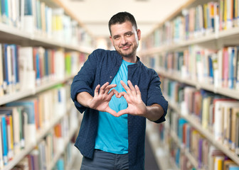 Young man wearing a blue outfit. Doing a heart gesture.