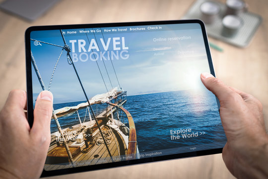 R&eacute;servation en ligne d'un hotel ou d'un voyage ou de vacances avec une tablette tenue en main par un homme