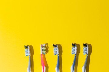 five multi-colored toothbrushes lie on a yellow background.