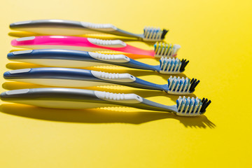 five multi-colored toothbrushes lie on a yellow background.