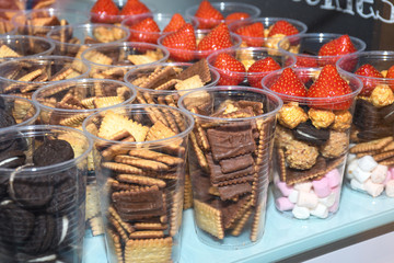 Red strawberries in a glass cup, along with biscuits, cupcakes, snacks ready to be served