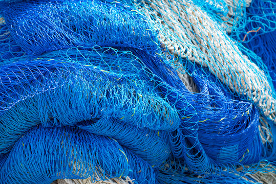 Full frame view of blue fishing nets lying in the sunshine filling the whole frame of the shot.